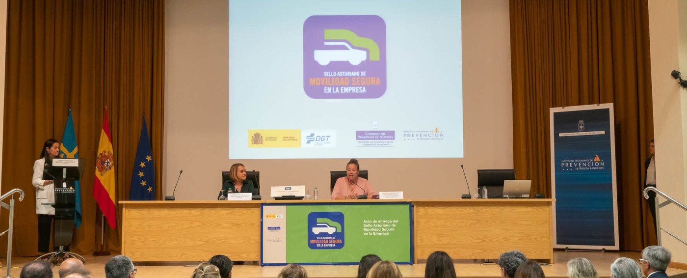 Dos ponentes dando una conferencia ante un público de movilidad segura en la empresa