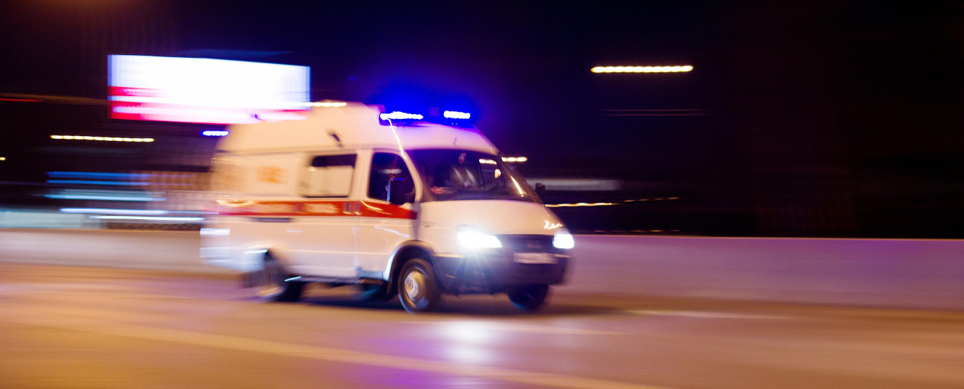 Ambulancia yendo deprisa por una carretera de ciudad por la noche