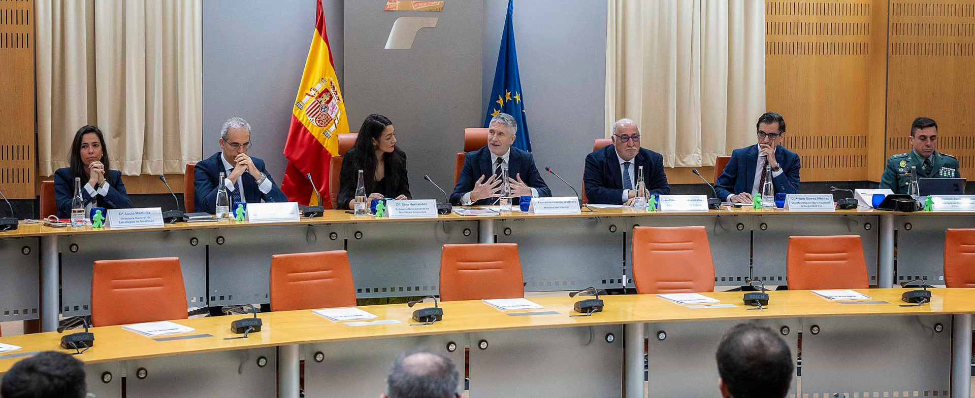 Reunión institucional con varias personas sentadas en una mesa larga; una persona habla en el centro. Al fondo se ven las banderas de España y de la Unión Europea. Reunión institucional con varias personas sentadas en una mesa larga; una persona habla en el centro. Al fondo se ven las banderas de España y de la Unión Europea.