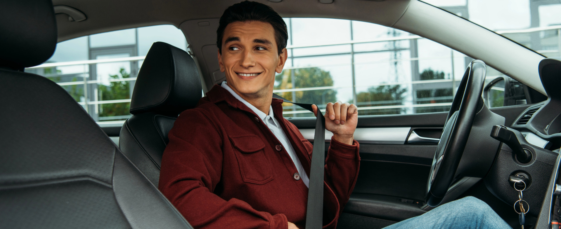 Hombre sentado en el interior de un coche abrochándose el cinturón de seguridad