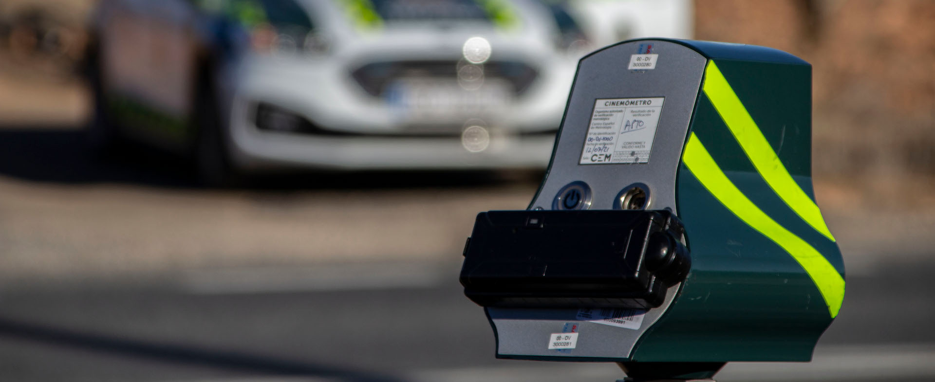 Veloláser en primer plano con un coche de la Guardia Civil desenfocado al fondo