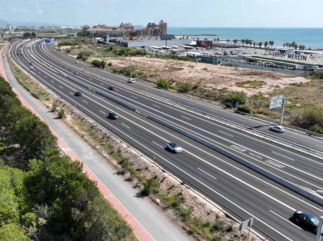 Imagen aérea de una autovía de costa con vehículos circulando con la playa de fondo.