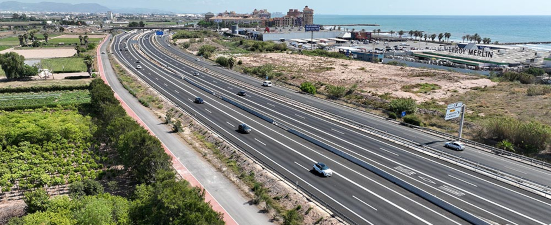 Imagen aérea de una autovía de costa con vehículos circulando con la playa de fondo.