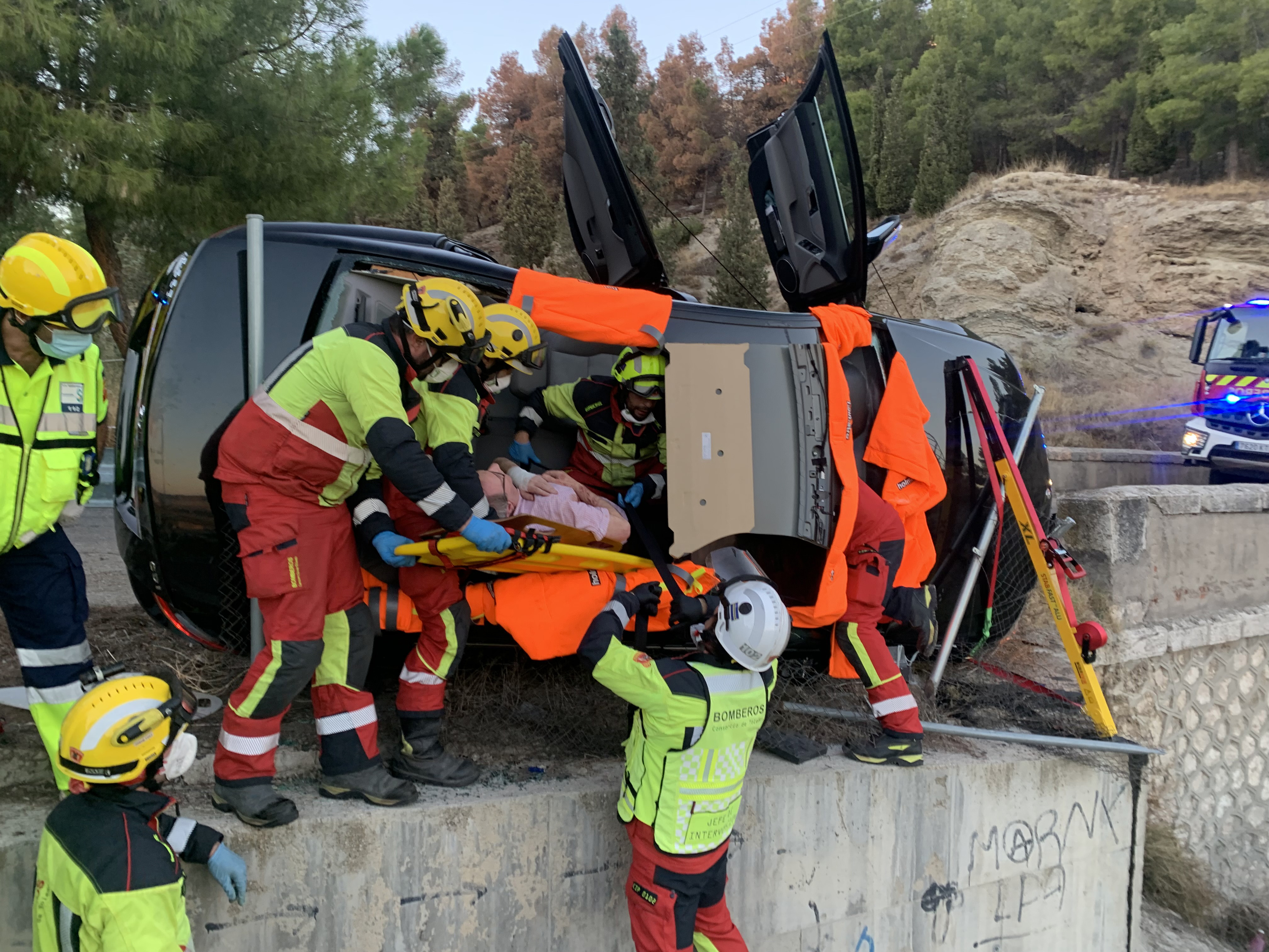 Grupo de bomberos rescatando a un hombre de su vehículo accidentado Grupo de bomberos rescatando a un hombre de su vehículo accidentado